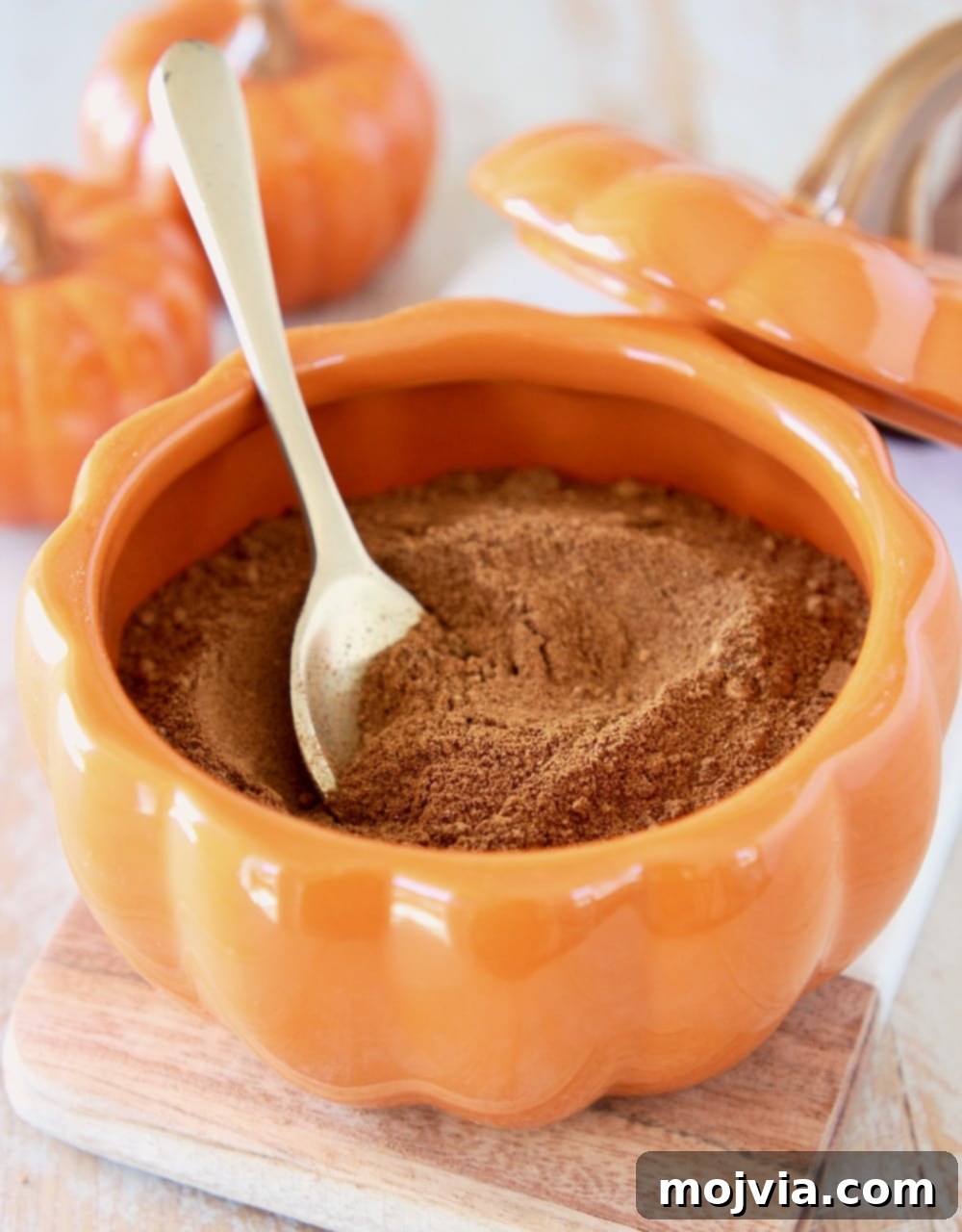 Cozy Homemade Pumpkin Spice 2 Homemade pumpkin pie spice in an orange pumpkin bowl with a small gold spoon and two small ceramic pumpkins