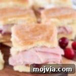 Ham sliders on hawaiian rolls on wood cutting board with fresh cranberries