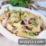 Creamy Instant Pot Beef Stroganoff 2 Beef Stroganoff with wide egg noodles topped with fresh parsley in white oval serving dish