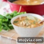 Thai coconut soup in bowl with potstickers, lime wedge and fresh cilantro