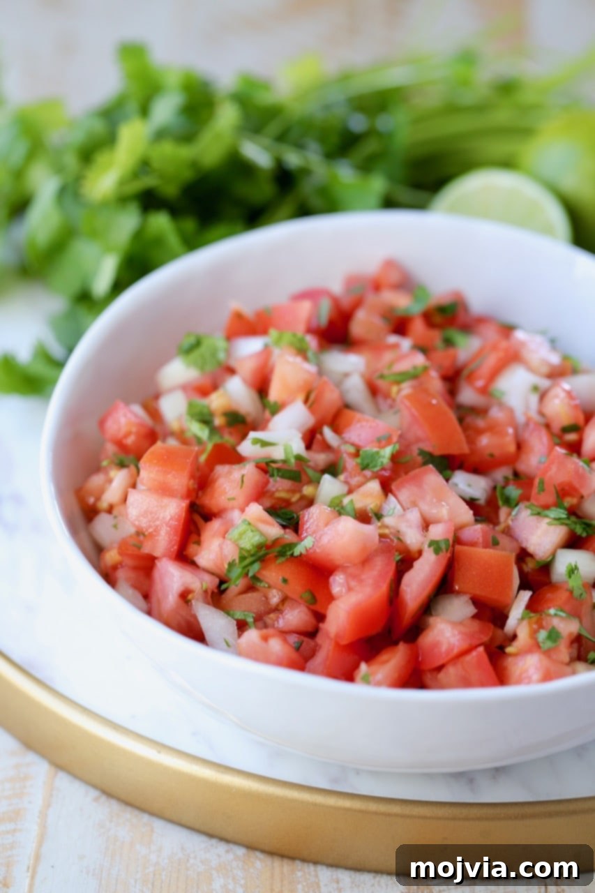 Fiesta Fresh Salsa 2 Pico de gallo in white bowl on marble serving tray, with fresh cilantro and limes in the background