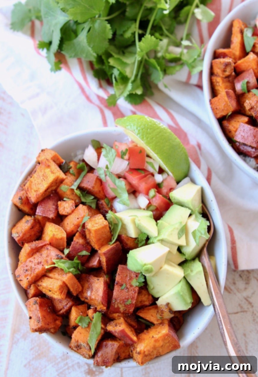 Southwest Vegan Sweet Potato Quinoa Fiesta 2 Roasted diced sweet potatoes in bowl with diced avocado, pico de gallo, lime wedge and copper fork, with orange and white striped towel underneath and fresh cilantro in the background