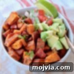Southwest Vegan Sweet Potato Quinoa Fiesta 5 Diced roasted sweet potatoes in quinoa bowl with diced avocado, pico de gallo and lime wedge with copper fork