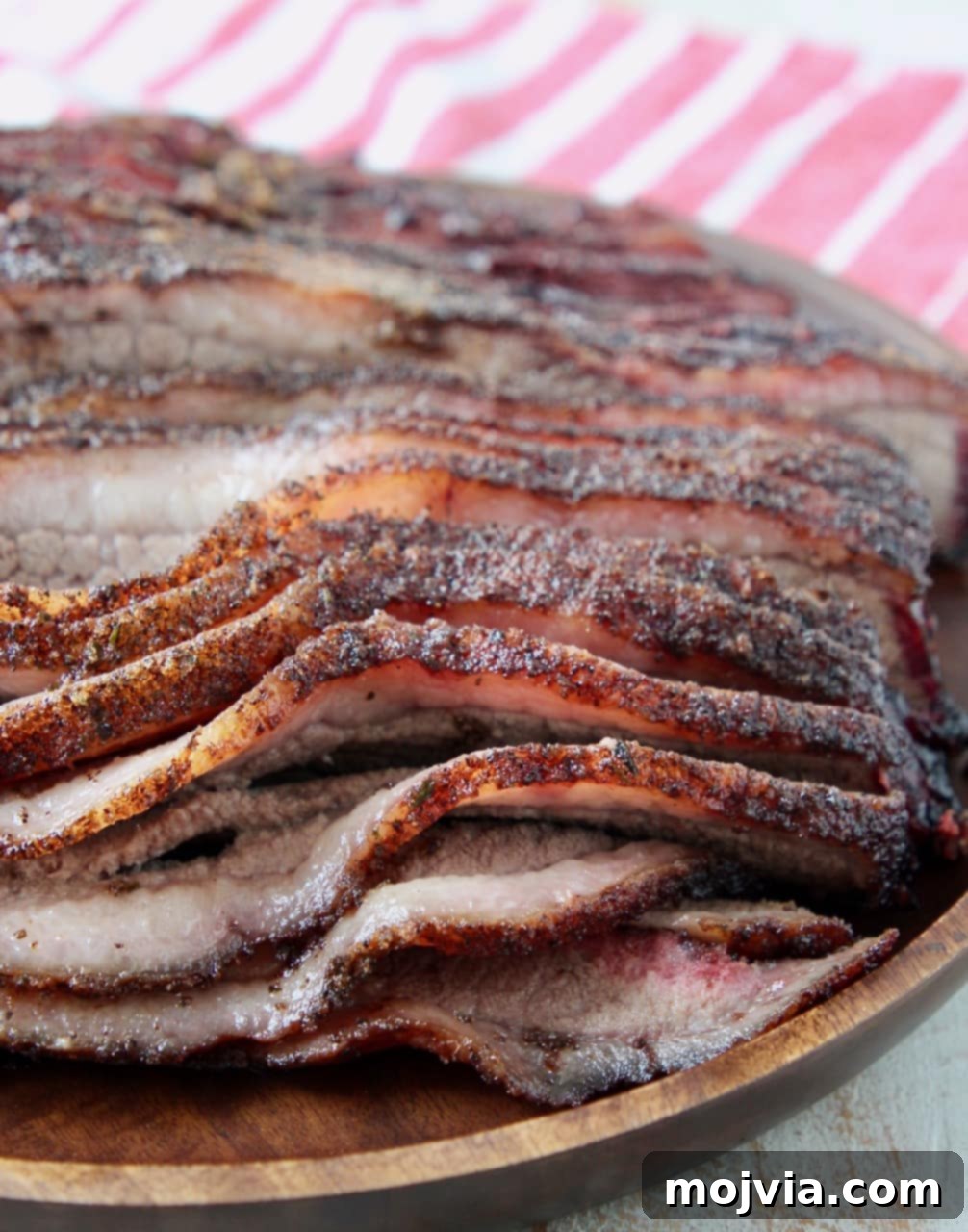 Close-up of tender, juicy sliced smoked brisket on a wooden tray, showcasing the perfect smoke ring and bark.