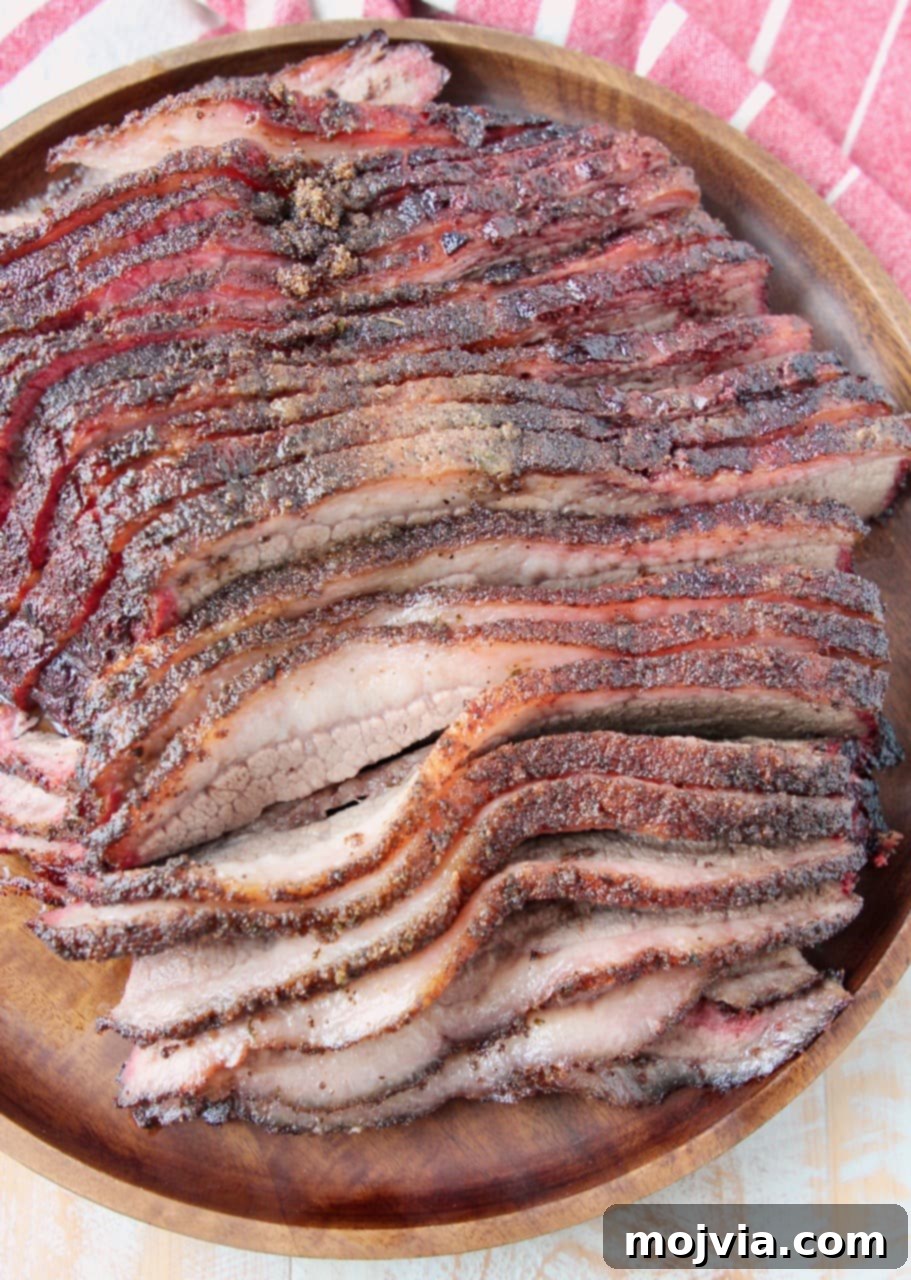 Overhead view of perfectly sliced smoked brisket arranged on a rustic round wooden serving tray, garnished subtly.