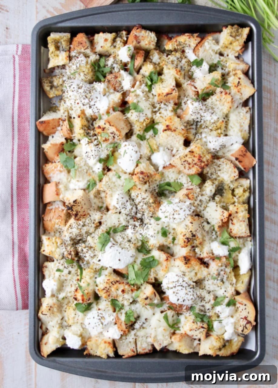 Finished cheesy garlic bread nachos on a baking sheet, beautifully golden with melted cheese and sprinkled with fresh chopped parsley.