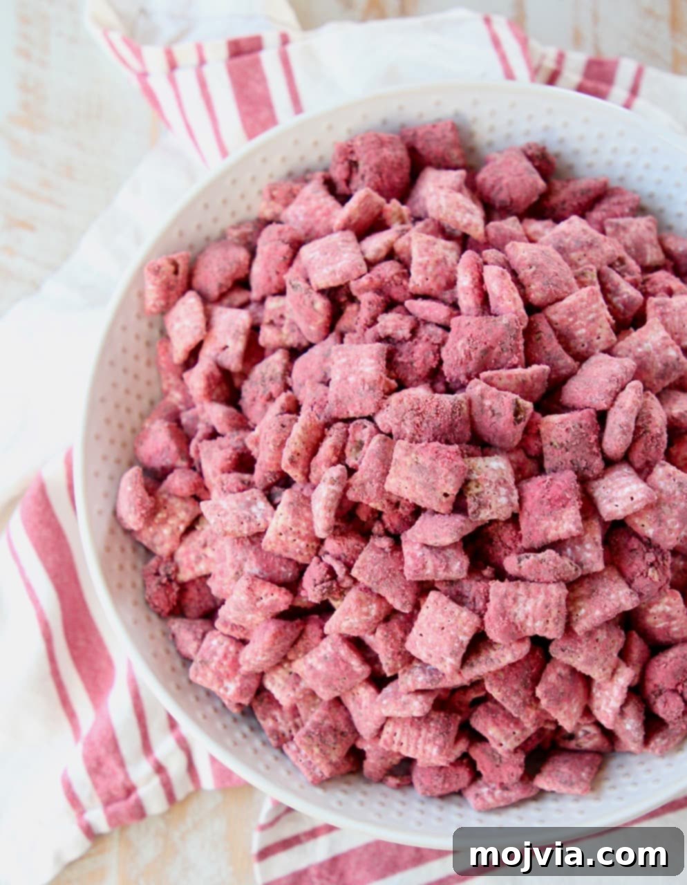 Crimson Velvet Crunch 4 Red velvet puppy chow in white bowl, sitting on white and red striped towel, showcasing the festive colors