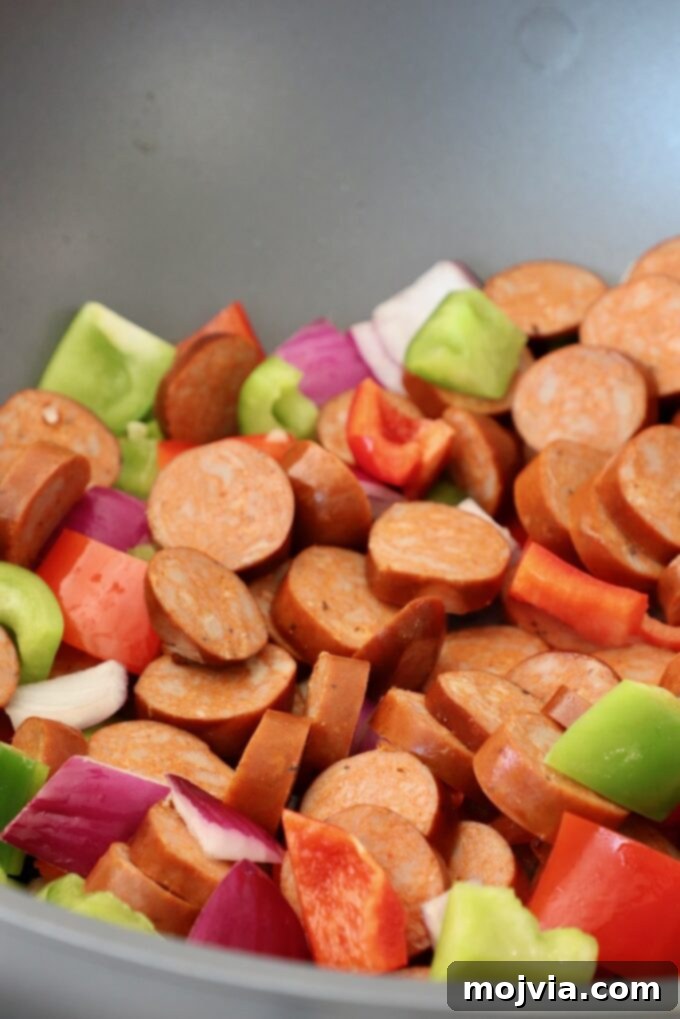 Spicy Cajun One-Pan Pasta 4 Sliced sausage, diced bell peppers, and onions sautéing in a large skillet.