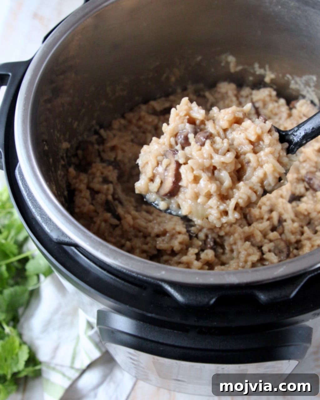 Velvety Instant Pot Mushroom Delight 4 A large serving spoon scooping creamy Instant Pot mushroom risotto directly from the Instant Pot, showing the rich texture and mushrooms.
