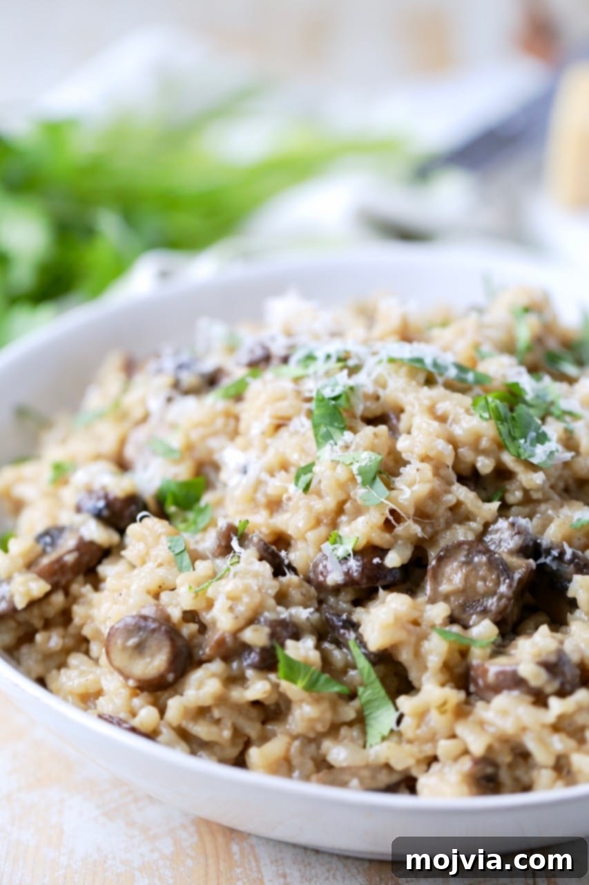 Velvety Instant Pot Mushroom Delight 5 A white bowl filled with Instant Pot mushroom risotto, garnished with Parmesan cheese, fresh herbs, and a spoon digging in.