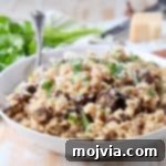Velvety Instant Pot Mushroom Delight 6 Close-up of creamy mushroom risotto in a bowl with a spoon, topped with grated Parmesan cheese.