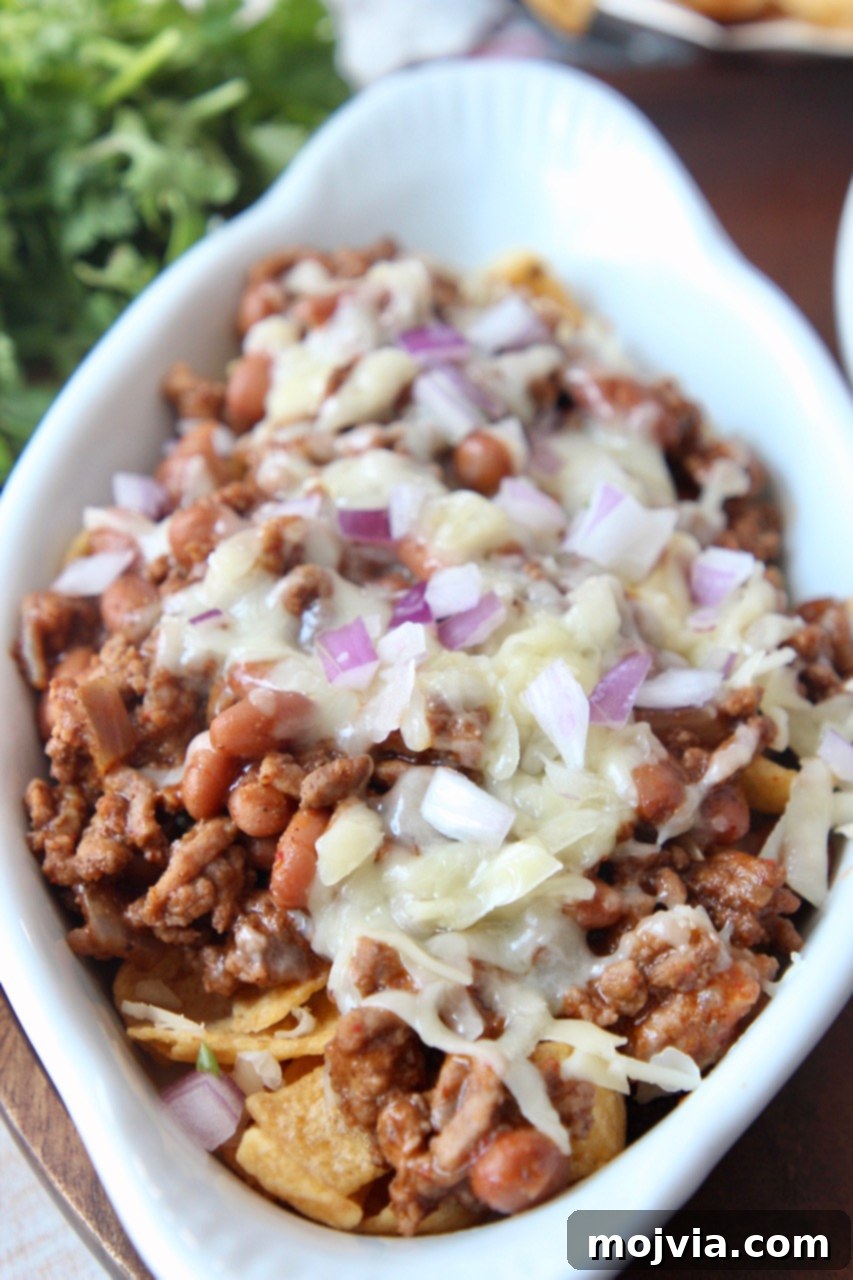 Tex-Mex Chili Crunch 2 Frito Chili Pie in a white baking dish, garnished with fresh herbs