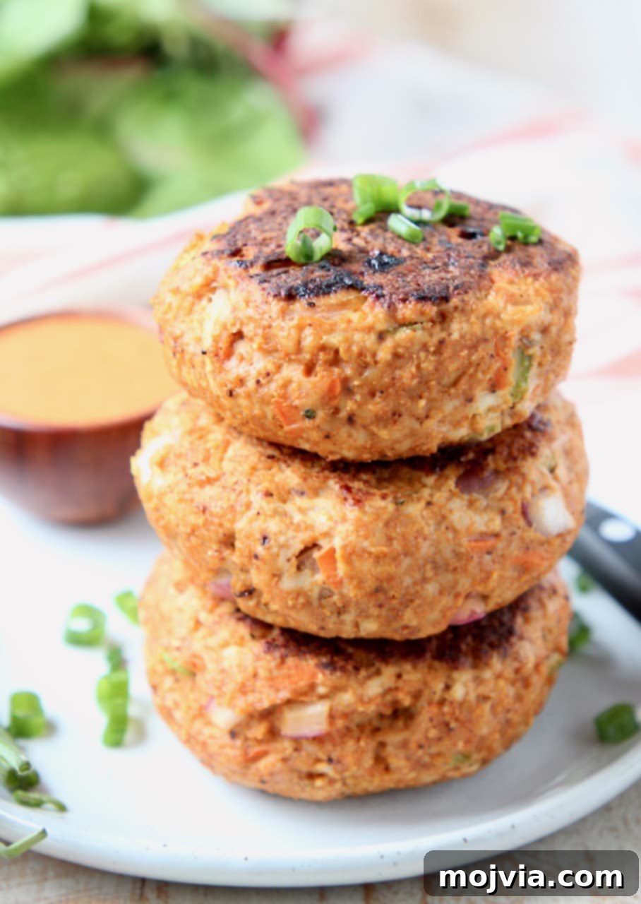 Fiery Buffalo Chicken Burgers 4 Buffalo chicken burger patties stacked on top of each other on white plate