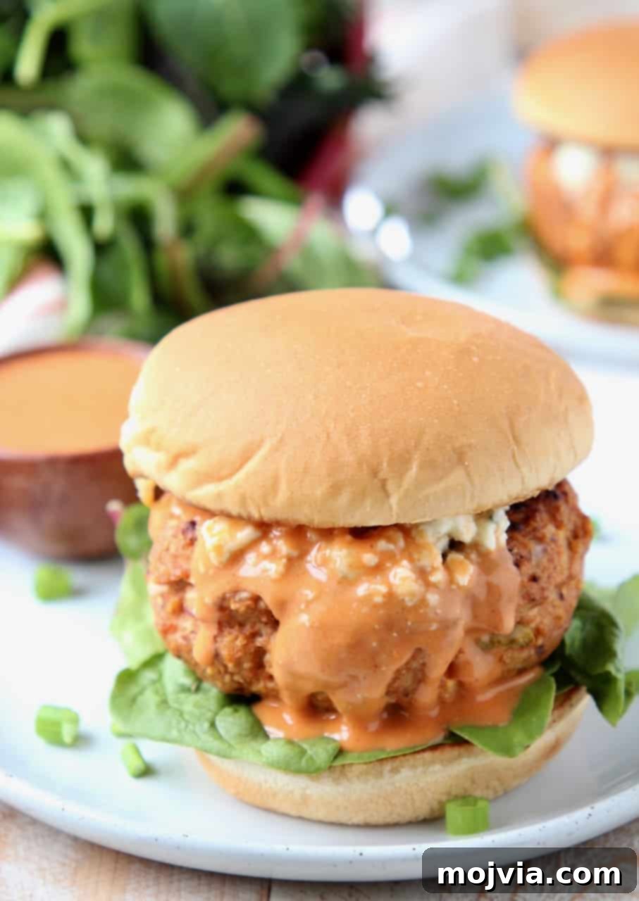 Fiery Buffalo Chicken Burgers 5 Buffalo chicken burger on bun covered in buffalo sauce sitting on plate