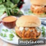 Chicken burger on bun with blue cheese crumbles and buffalo wing sauce