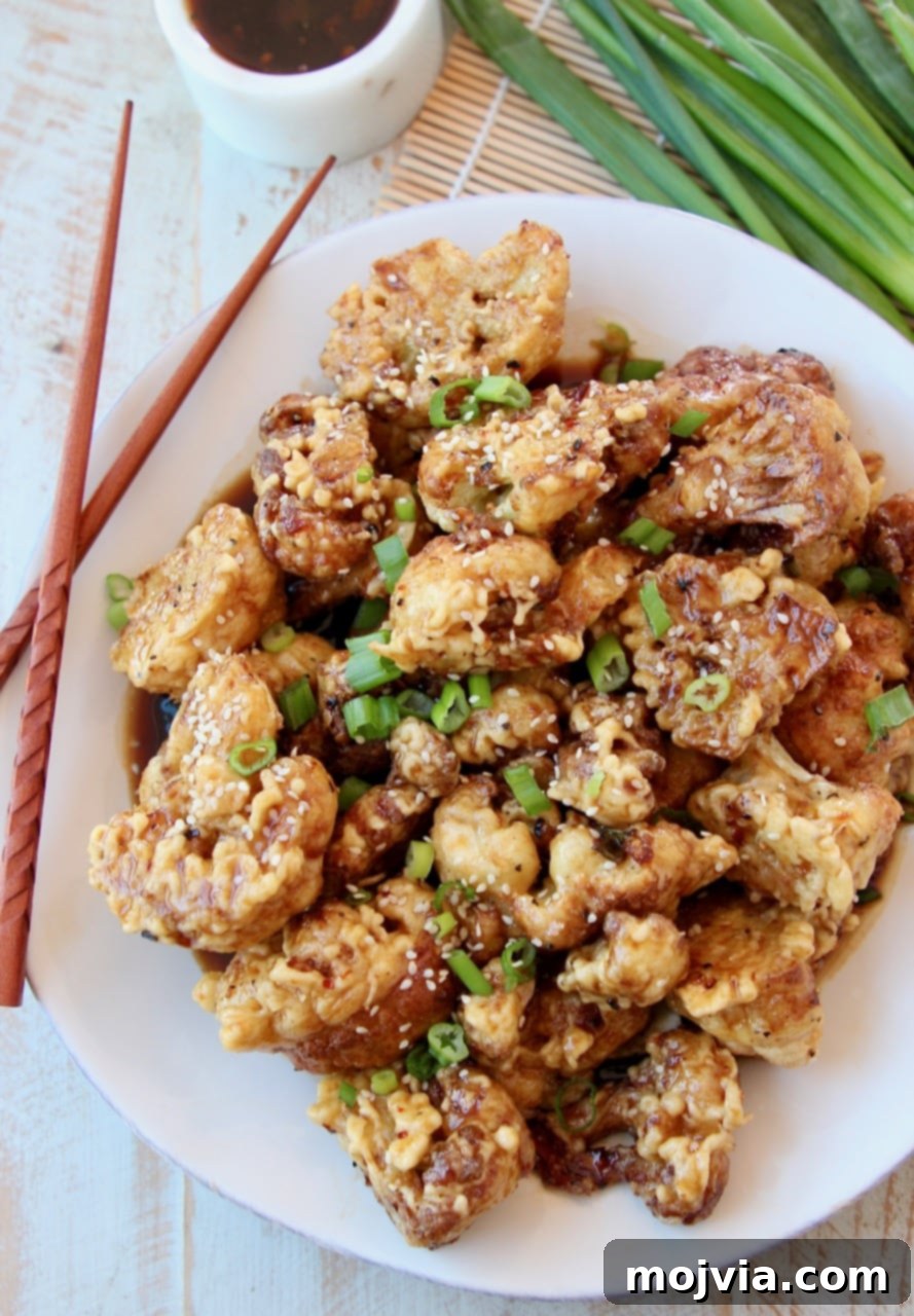 Gochujang Glazed Cauliflower Wings 3 Fried Cauliflower piled up on white plate topped with Korean BBQ Sauce and diced green onions