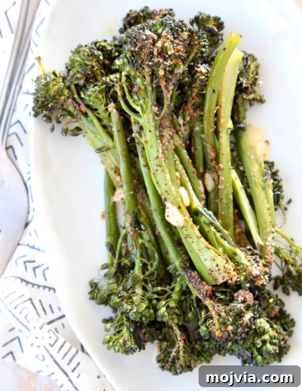 Golden Roasted Garlic Parmesan Broccolini 2 Roasted Garlic Parmesan Broccolini stacked on a white plate, showcasing its vibrant green color and savory crust.
