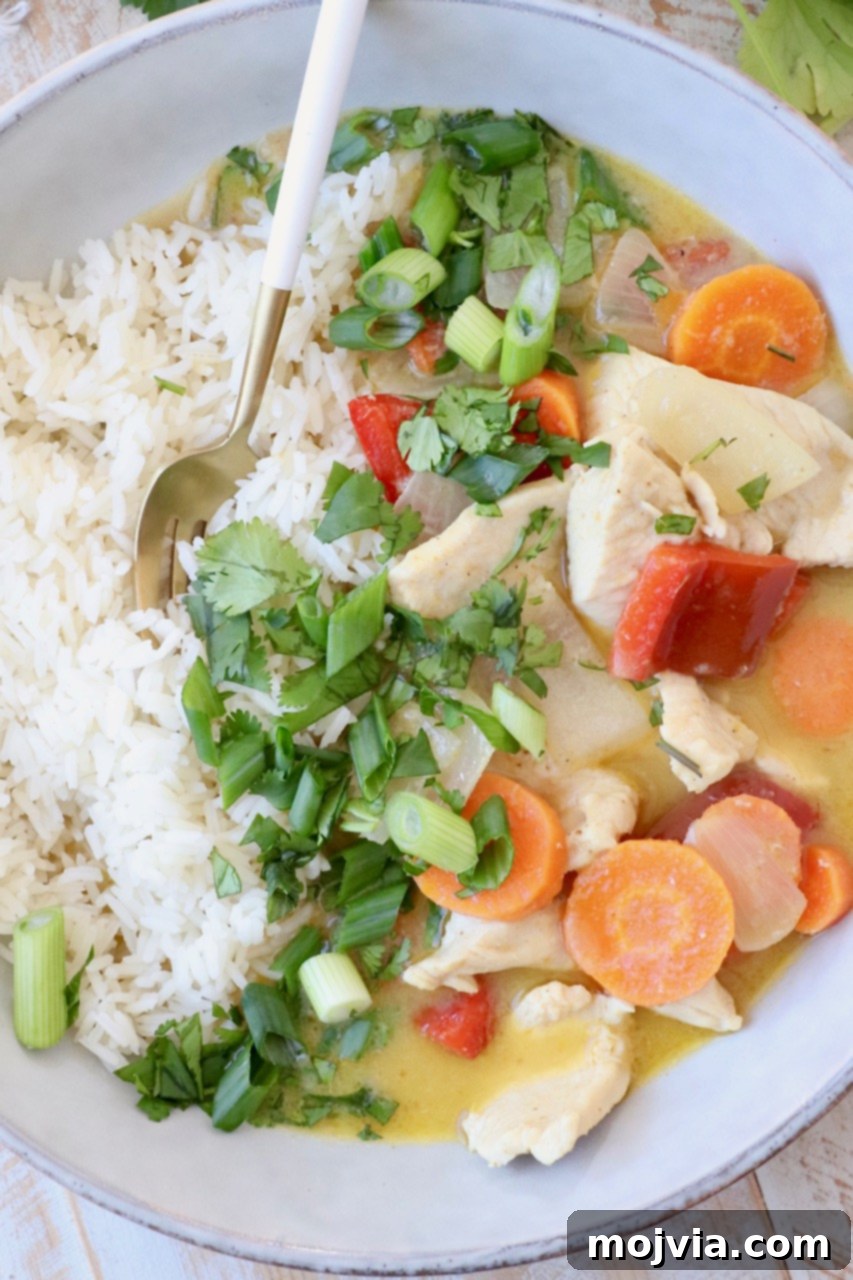 vegetables and chicken in yellow curry sauce in bowl with cooked white rice
