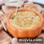 Pumpkin hummus in orange bowl with gold spoon