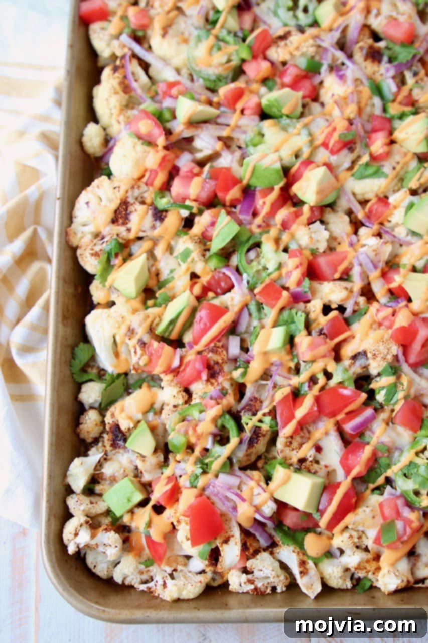 Nacho Florets 2 Overhead shot of cauliflower nachos on a baking sheet with chipotle cream sauce drizzled on top
