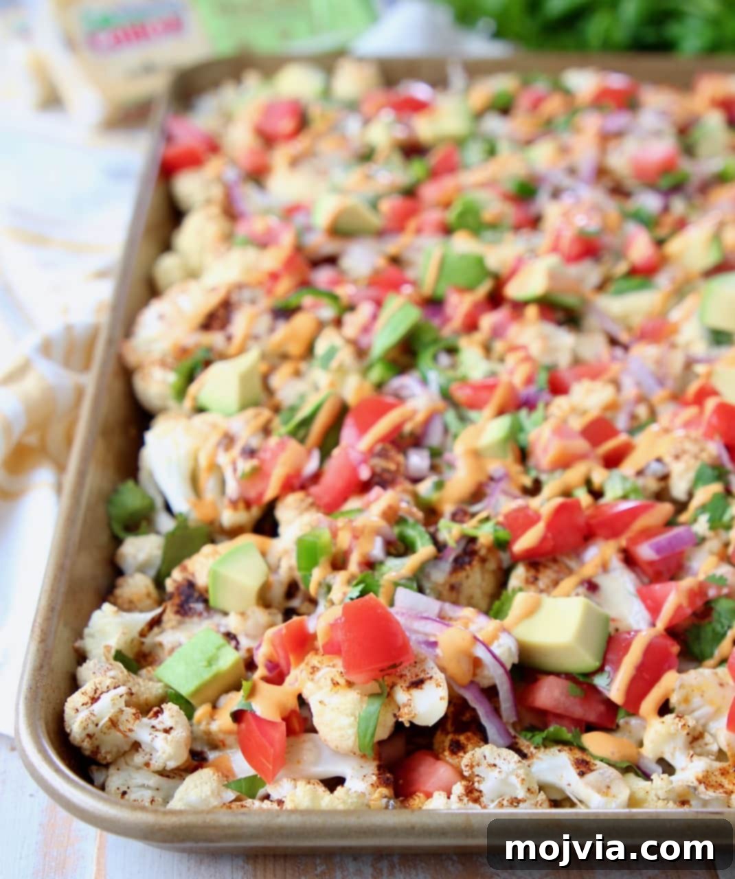 Nacho Florets 3 Cauliflower nachos on baking sheet topped with diced tomatoes and avocado