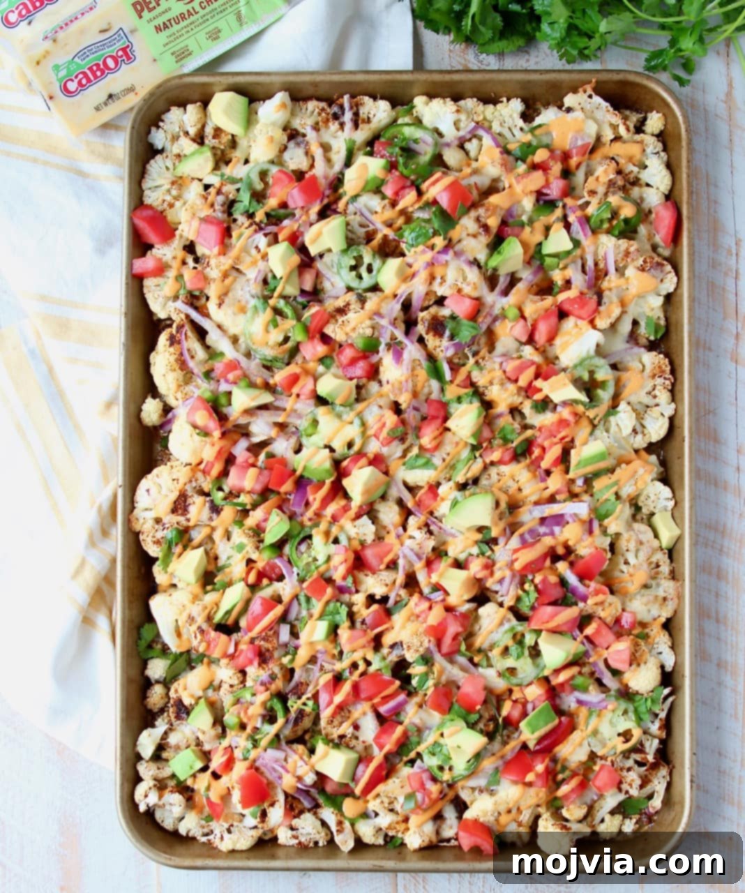 Nacho Florets 4 Overhead shot of cauliflower nachos on sheet pan with fresh cilantro and sliced jalapenos