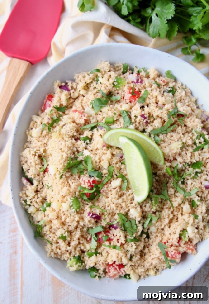 A beautifully presented white bowl of Mexican couscous, garnished with fresh lime wedges on top, highlighting the vibrant colors and appealing texture of the dish.