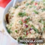 Couscous in bowl with white and gold spoon, topped with chopped cilantro