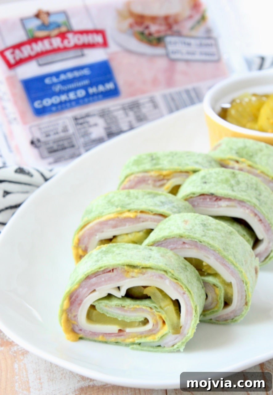 Tortilla wrapped pinwheel sandwiches on white plate, neatly arranged