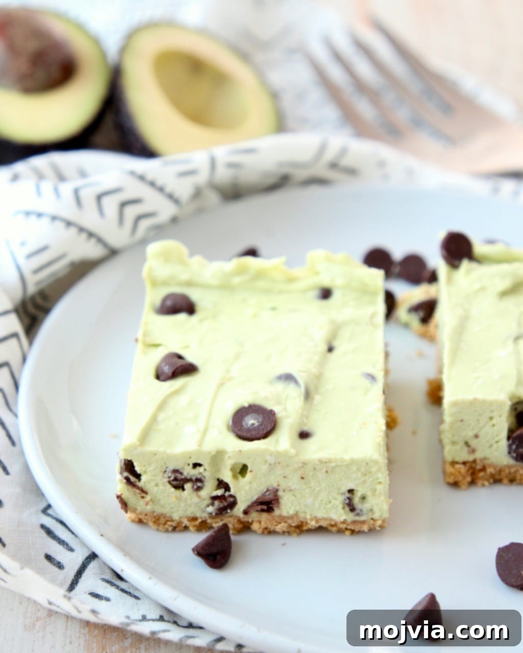 Effortless Avocado Bliss Bars 5 Avocado no bake cheesecake bars generously topped with chocolate chips, presented beautifully on a plate, ready to be enjoyed.