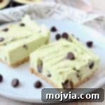 Frozen avocado cheesecake bars on plate with chocolate chips, a perfect chilled dessert.