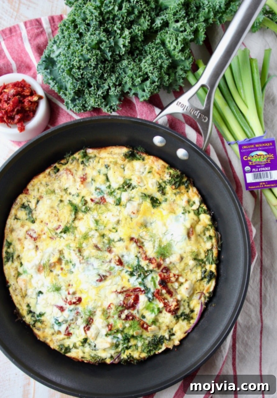 Sun-Kissed Mediterranean Frittata 6 Whole vegetarian frittata in a skillet, surrounded by fresh kale and green onions, ready to be sliced and served.