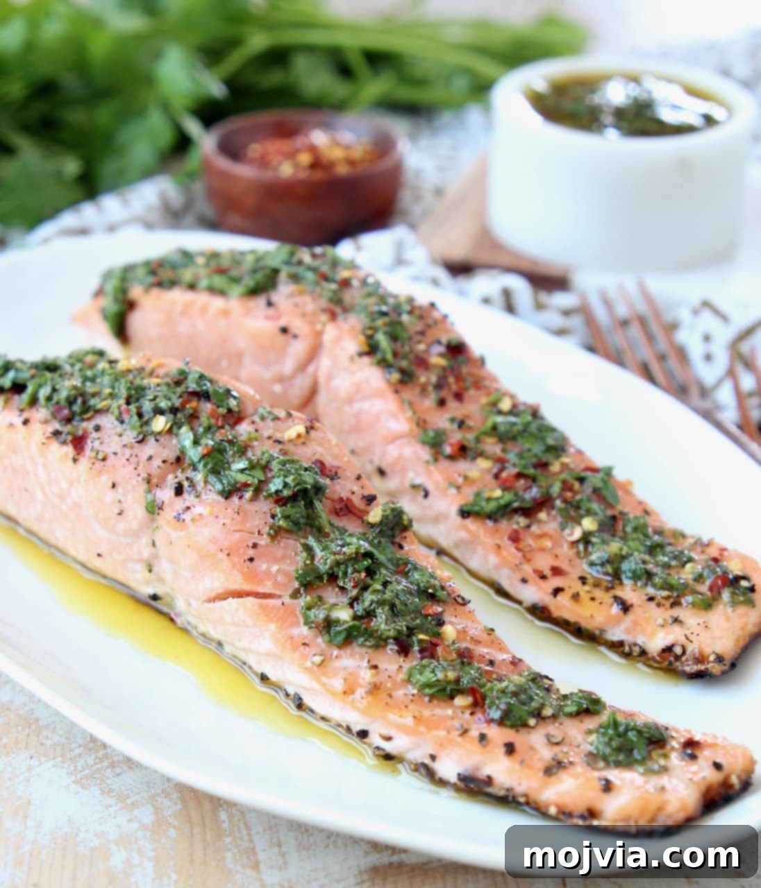 Slices of salmon on plate topped with chimichurri sauce