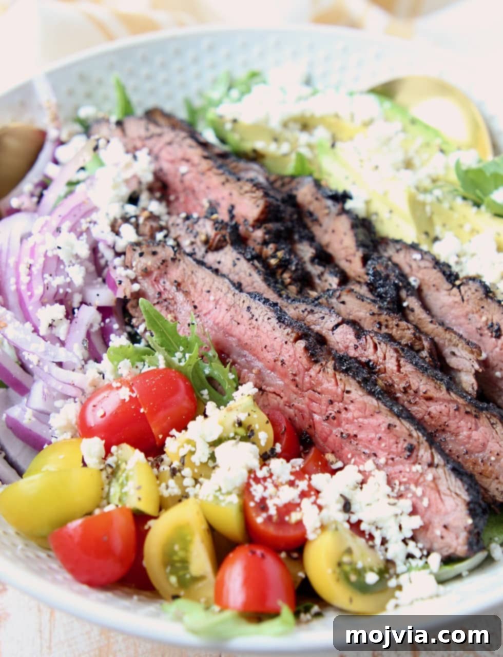 Sliced steak on a salad with cherry tomatoes, onions and goat cheese