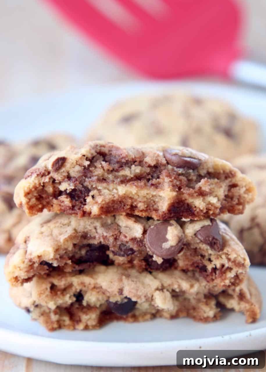 Nutella Swirl Chocolate Chip Cookies 2 Nutella chocolate chip cookies broken in half and stacked on top of each other, showcasing their chewy interior and Nutella swirl