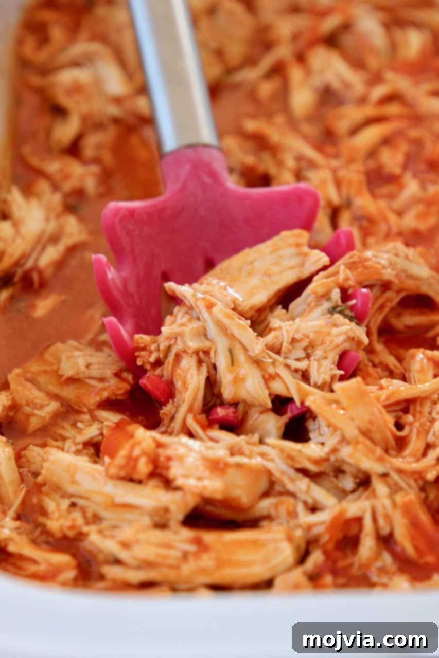 Set It and Forget It Buffalo Chicken 2 Shredded buffalo chicken in crock pot with red spoon