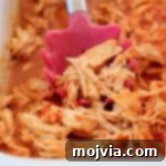 Set It and Forget It Buffalo Chicken 10 Shredded buffalo chicken with red serving spoon