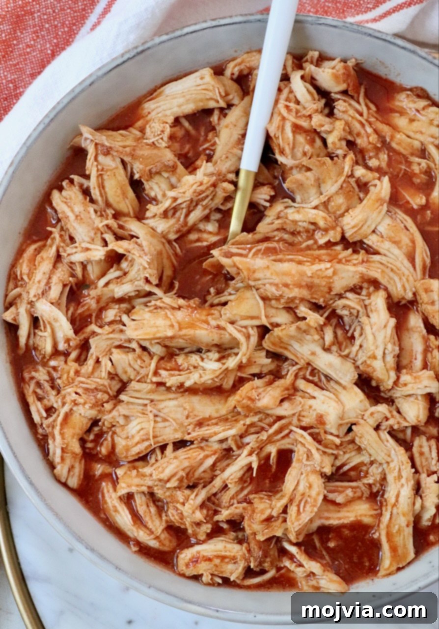 Set It and Forget It Buffalo Chicken 4 shredded chicken with buffalo sauce in bowl with fork