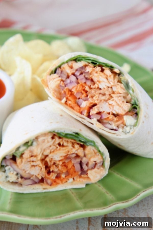 Set It and Forget It Buffalo Chicken 5 Buffalo chicken wrap cut in half and leaning on each other on green plate with potato chips