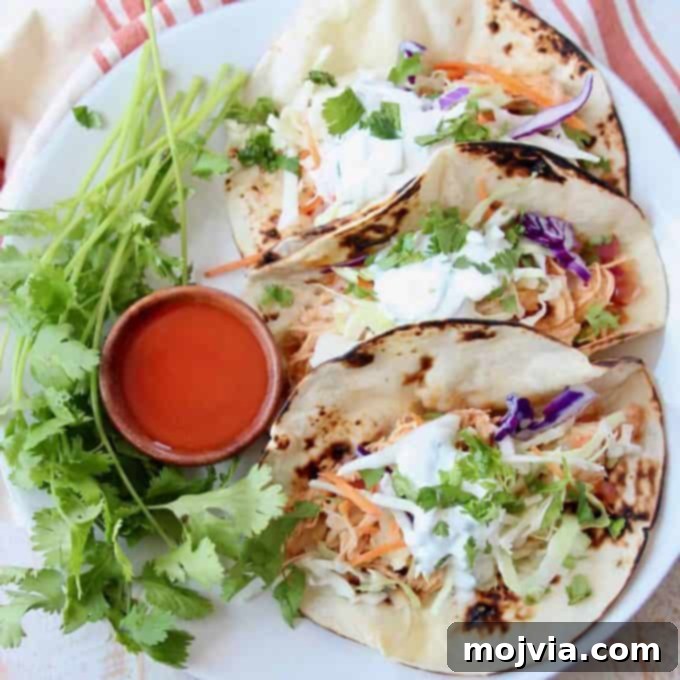 Set It and Forget It Buffalo Chicken 6 Tacos on plate with small wooden bowl of buffalo sauce on the side