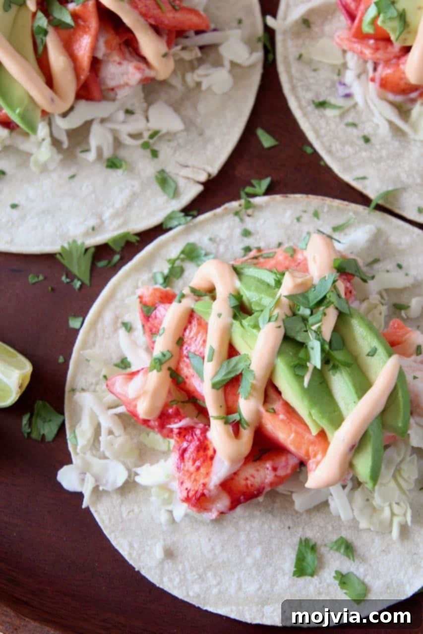 Decadent Lobster Tacos 2 Freshly prepared lobster tacos on a rustic wooden serving tray, garnished with lime wedges and a halved avocado.