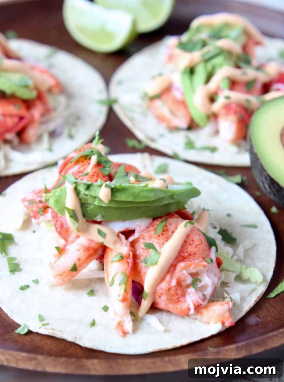 Decadent Lobster Tacos 4 Close-up of lobster tacos adorned with creamy avocado slices on a wooden serving tray, showcasing the vibrant ingredients.