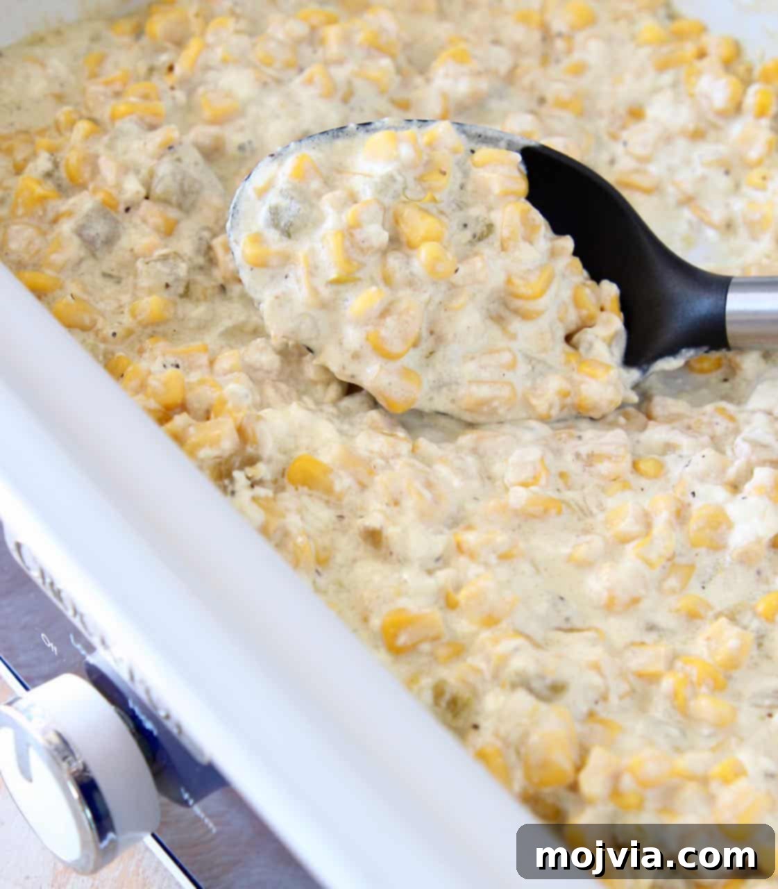 Velvety Slow Cooker Creamed Corn 5 Creamed corn in slow cooker with serving spoon, ready for guests