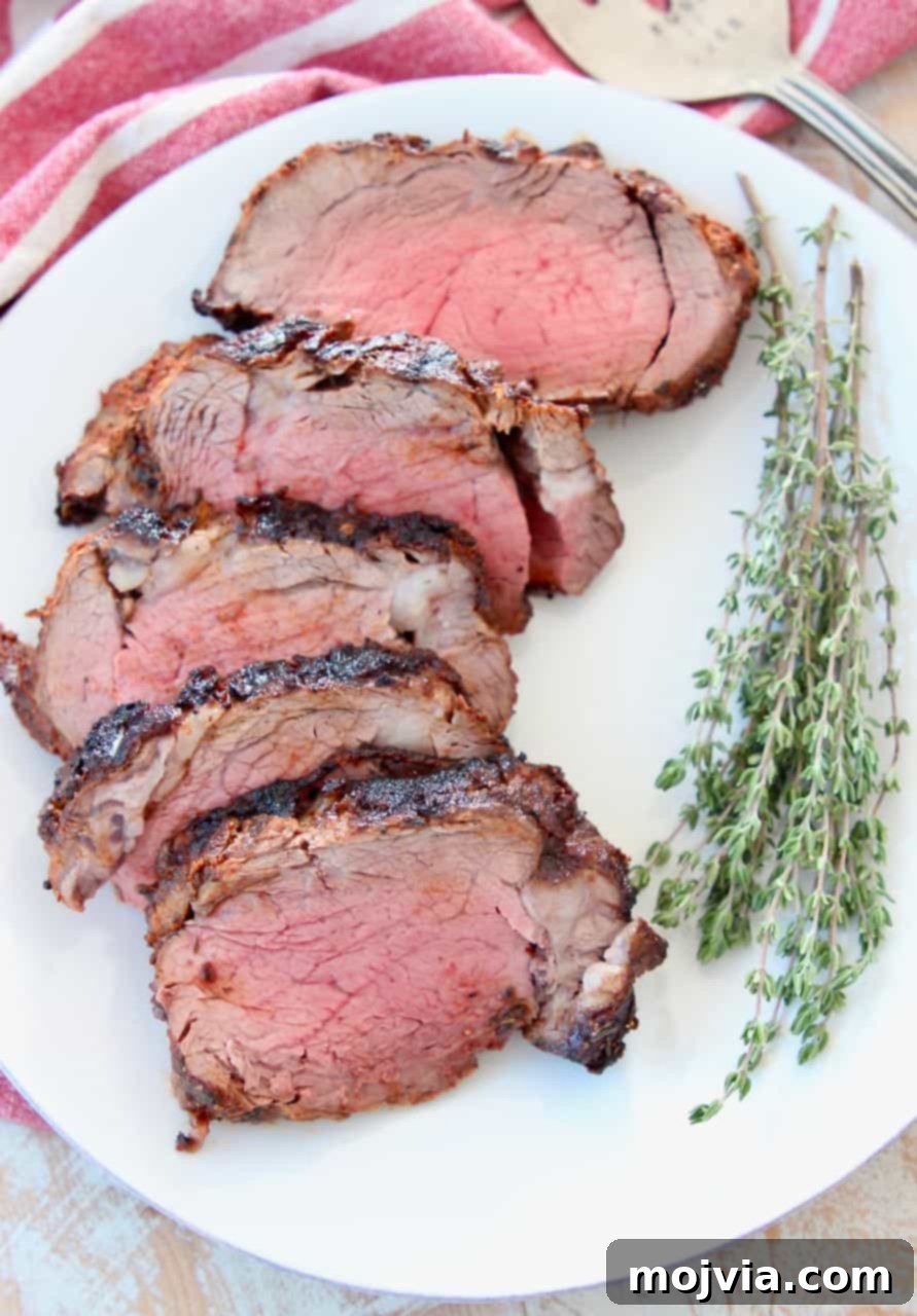 Spicy Crusted Beef Tenderloin 3 Slices of blackened beef tenderloin on white plate with fresh herbs