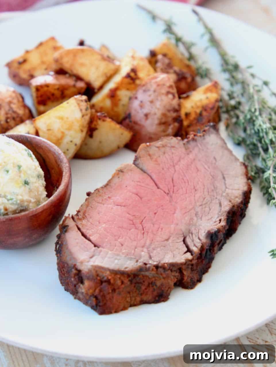 Spicy Crusted Beef Tenderloin 4 Thick sliced beef tenderloin on plate with herbs, potatoes and butter