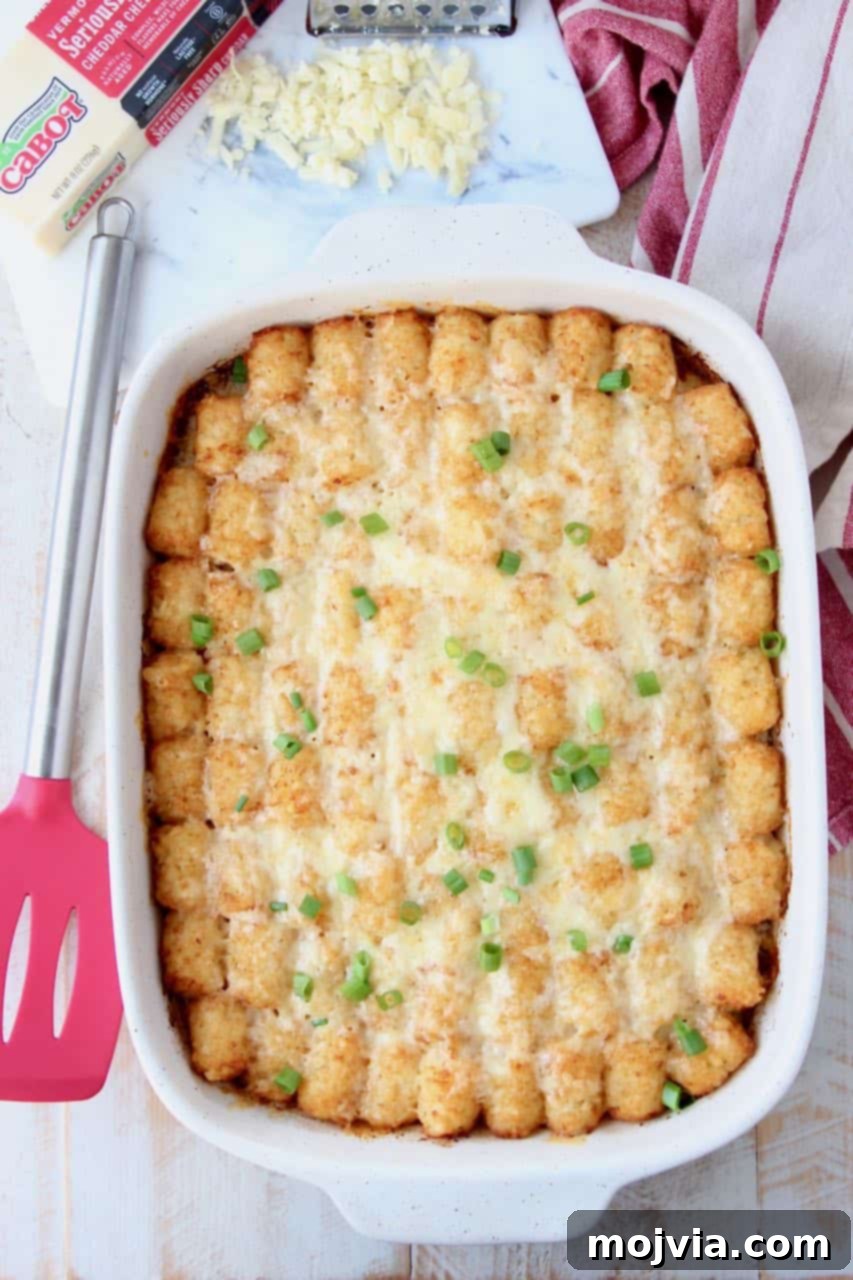 Golden Cheesy Tater Tot Bake 2 Breakfast tater tot casserole in casserole dish with red spatula on the side