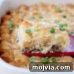 Golden Cheesy Tater Tot Bake 7 Slice of breakfast tater tot casserole being lifted out of the baking dish with a red spatula