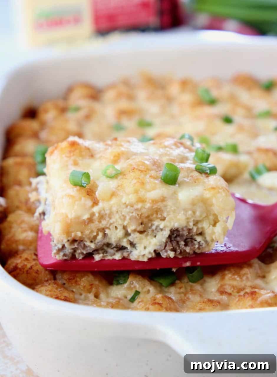 Golden Cheesy Tater Tot Bake 3 Slice of breakfast casserole on spatula coming out of the casserole dish