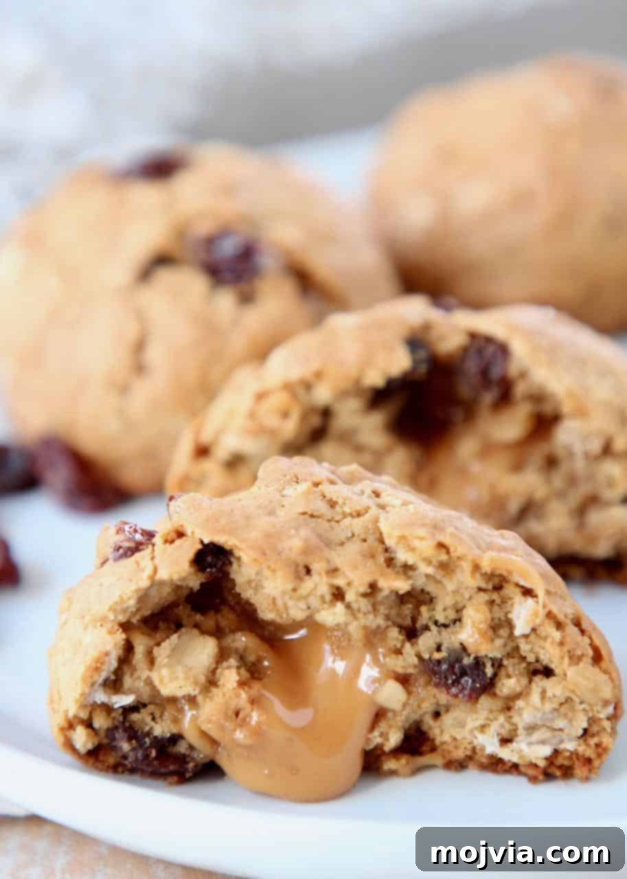 Caramel Core Oatmeal Raisin Cookies 2 A perfectly baked oatmeal raisin cookie, cut in half to reveal a luscious, oozing caramel filling. The warm, gooey caramel contrasts beautifully with the soft, chewy oat and raisin cookie.