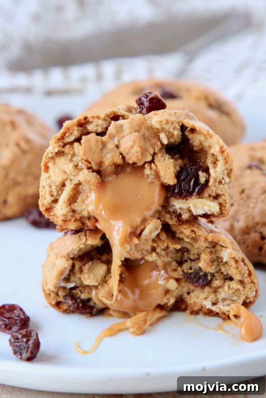 Caramel Core Oatmeal Raisin Cookies 3 A stack of golden-brown oatmeal raisin cookies, each expertly cut in half to showcase the rich, melted caramel center. The textures look soft and inviting, promising a delightful bite.